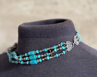 Multi-strand necklace with turquoise and silver beads featuring a large sterling silver pendant with intricate turquoise inlay and decorative elements, including hanging charms. Marked ‘925’ for sterling silver purity. This necklace measures, 19.5” and has a total approx. weight of 205.91 grams.