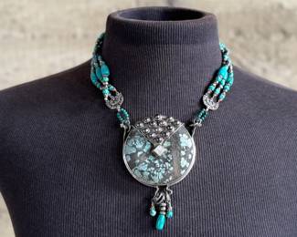 Multi-strand necklace with turquoise and silver beads featuring a large sterling silver pendant with intricate turquoise inlay and decorative elements, including hanging charms. Marked ‘925’ for sterling silver purity. This necklace measures, 19.5” and has a total approx. weight of 205.91 grams.