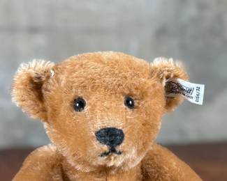 Steiff original teddy bear featuring brown mohair fur and a classic black stitched nose. Retains the trademark Steiff tag in the ear and button. In good condition with visible iconic craftsmanship.