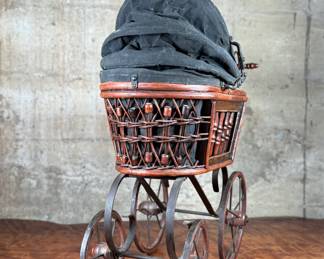 This lot features a beautiful antique Victorian-style doll carriage made from wicker, wood, and metal. This piece measures, 17.5” H x 19” W x 7” D.