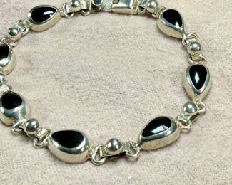 This lot features a vintage sterling silver & onyx bracelet that measures, 8.5” with a total approx. weight of 27.18 grams.