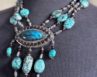 Sterling silver statement necklace featuring an intricate design with various gemstones. The hallmark ‘925’ is stamped on the reverse side, affirming its sterling silver composition. The piece includes multiple strands and pendants accented with gemstones. In good condition and designed with a secure clasp for wearability. This necklace measures, 18” with a total approx. weight of 356.22 grams.