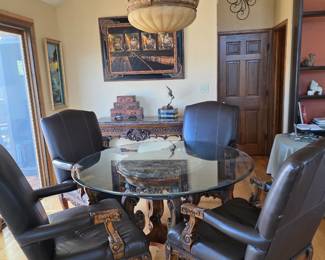 Round glass pedestal table with four leather chairs.
