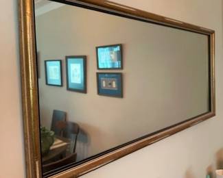 Vintage wall mirror featuring a gold colored frame.