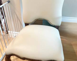 French Provincial cabriole leg chairs freshly reupholstered in cream faux leather. Host chairs feature brass nailhead trim. 