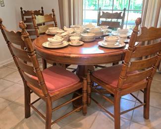 Extendable round wood pedestal dining table and wooden ladder-back dining chairs