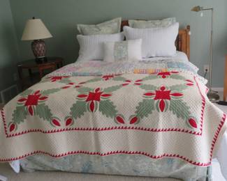 Full bed with headboard. Antique red and green applique quilt with sawtooth border.