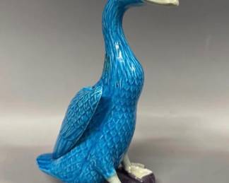 Vintage turquoise glazed duck figurine stands on glazed purple base