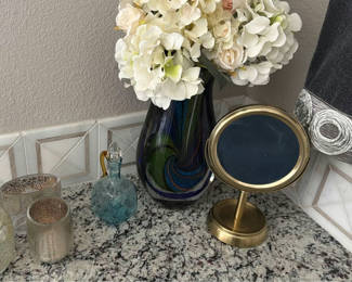 Lot 404: Hydrangea bouquet in blue glass vase with decorative bottles and brass mirror
