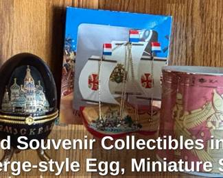 Assorted Souvenir Collectibles including Fabergestyle Egg, Miniature Ship, Egyptian Mug, Matryoshka Doll, Cologne Cathedral Tin, and Camel Figurine