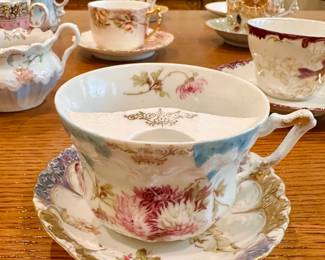 Mustache Cups, most with matching saucers. Porcelain, hand-painted. Popularized in the Victorian era (circa 1850–1910), they served a practical function, preventing wax from melting and keeping facial hair clean.