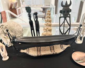 Gambela canoe basket , hand woven, black canoe shaped bowl help by long metal silhouette, stone, like sculpture of mother and baby elephant