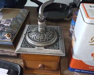 vintage coffee grinder featuring an ornate cast iron top and a wooden base with a drawer.
