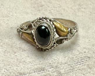 This lot features a vintage handcrafted ring made of sterling silver with an onyx center stone and gold accents. The purity of the gold is untested. This ring comes in a size 7 with a total approx. weight of 2.28 grams.