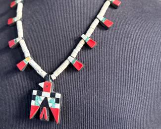 This lot features an antique Santo Domingo Pueblo (Kewa) Thunderbird necklace, an iconic style frequently made during the Depression era using repurposed materials like plastic from battery casings, phonograph records, and turquoise. This necklace has mosaic inlay typically utilizing turquoise, coral, and black jet (often repurposed plastic). These necklaces are highly collectible examples of Southwestern cultural heritage and resourcefulness. Handcrafted by artists from the Kewa (Santo Domingo) Pueblo, with many historic examples dating back to the 1920s–1940s. Measures, 22”.