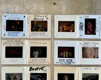 Vintage 35mm slides primarily organized in a transparent holder. Each slide features labels with the name “Richard Creamer” and addresses in Beverly Hills and Los Angeles, CA. Subjects documented include notable music acts such as The Police, David Bowie, ELO, and others. Handwritten annotations accompany several slides. Great condition for archival or display purposes.
