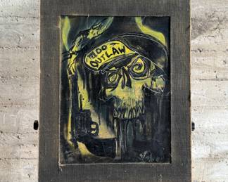 Media artwork on board depicting a skull wearing a hat with ‘100 Outlaw’ written on it. The piece features dark tones accented with striking yellow highlights. There is a gun and a bird incorporated into the imagery. The frame has wear at the edges, and the artist’s signature is present in the lower right corner. Mounted without glass covering and measures, 30” H x 24” W.