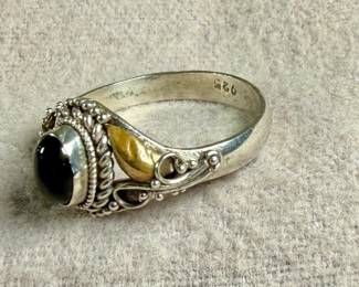This lot features a vintage handcrafted ring made of sterling silver with an onyx center stone and gold accents. The purity of the gold is untested. This ring comes in a size 7 with a total approx. weight of 2.28 grams.