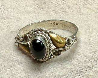This lot features a vintage handcrafted ring made of sterling silver with an onyx center stone and gold accents. The purity of the gold is untested. This ring comes in a size 7 with a total approx. weight of 2.28 grams.