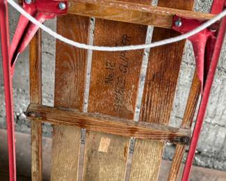 Wooden Flexible Flyer Yankee Clipper sled featuring steel runners painted in red and a wooden deck with printed branding. The sled includes a wooden crossbar for steering and a rope control. Signs of wear consistent with age and use, including scratches and minor rust on metal parts, are visible. A classic item for collectors or enthusiasts of vintage winter gear. Measures, 44” H x 20.5” W.