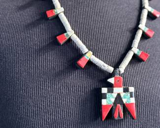 This lot features an antique Santo Domingo Pueblo (Kewa) Thunderbird necklace, an iconic style frequently made during the Depression era using repurposed materials like plastic from battery casings, phonograph records, and turquoise. This necklace has mosaic inlay typically utilizing turquoise, coral, and black jet (often repurposed plastic). These necklaces are highly collectible examples of Southwestern cultural heritage and resourcefulness. Handcrafted by artists from the Kewa (Santo Domingo) Pueblo, with many historic examples dating back to the 1920s–1940s. Measures, 22”.
