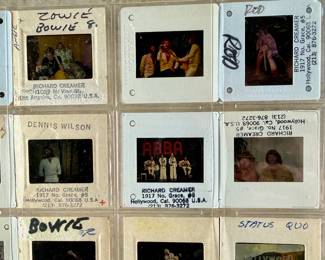 Vintage 35mm slides primarily organized in a transparent holder. Each slide features labels with the name “Richard Creamer” and addresses in Beverly Hills and Los Angeles, CA. Subjects documented include notable music acts such as The Police, David Bowie, ELO, and others. Handwritten annotations accompany several slides. Great condition for archival or display purposes.