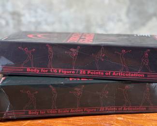 Two boxed Super Flexible Female Seamless Body figures designed for 1/6th scale action figures. Each features 28 points of articulation and a stainless steel skeleton. One box indicates “Med Bust, Pale, Suntan, ” while the other lists “Large Bust, Mid Bust, Tan, Suntan.” Both items are in original packaging with minor signs of handling on the boxes.