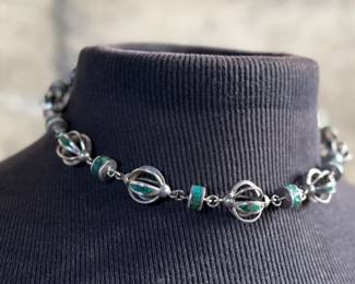 This lot features a beautiful necklace crafted from sterling silver and inlaid Malachite. Measures, 17” with a total approx. weight of 78.59 grams.