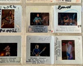 Vintage 35mm slides primarily organized in a transparent holder. Each slide features labels with the name “Richard Creamer” and addresses in Beverly Hills and Los Angeles, CA. Subjects documented include notable music acts such as The Police, David Bowie, ELO, and others. Handwritten annotations accompany several slides. Great condition for archival or display purposes.