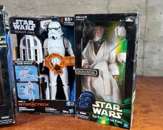 Three Star Wars action figures, all in original unopened packaging. Includes Chewbacca with removable restraints, Imperial Stormtrooper from the Interactech series with sound effects, and Obi-Wan Kenobi from The Power of the Force series. Each figure retains original branding and age recommendations.