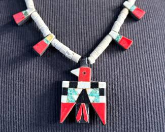 This lot features an antique Santo Domingo Pueblo (Kewa) Thunderbird necklace, an iconic style frequently made during the Depression era using repurposed materials like plastic from battery casings, phonograph records, and turquoise. This necklace has mosaic inlay typically utilizing turquoise, coral, and black jet (often repurposed plastic). These necklaces are highly collectible examples of Southwestern cultural heritage and resourcefulness. Handcrafted by artists from the Kewa (Santo Domingo) Pueblo, with many historic examples dating back to the 1920s–1940s. Measures, 22”.