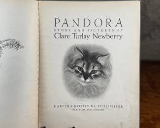 First edition of ‘Pandora, ‘ written and illustrated by Clare Turlay Newberry, published by Harper & Brothers. The book showcases charming illustrations and a story centered around a cat. It features a worn illustrated hardcover with signs of age-related wear, including scuffs and edge fraying. The interior remains intact with detailed illustrations and text reflective of Newberry’s style.