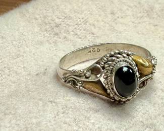 This lot features a vintage handcrafted ring made of sterling silver with an onyx center stone and gold accents. The purity of the gold is untested. This ring comes in a size 7 with a total approx. weight of 2.28 grams.