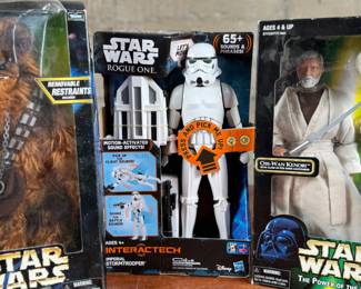 Three Star Wars action figures, all in original unopened packaging. Includes Chewbacca with removable restraints, Imperial Stormtrooper from the Interactech series with sound effects, and Obi-Wan Kenobi from The Power of the Force series. Each figure retains original branding and age recommendations.