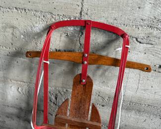 Wooden Flexible Flyer Yankee Clipper sled featuring steel runners painted in red and a wooden deck with printed branding. The sled includes a wooden crossbar for steering and a rope control. Signs of wear consistent with age and use, including scratches and minor rust on metal parts, are visible. A classic item for collectors or enthusiasts of vintage winter gear. Measures, 44” H x 20.5” W.