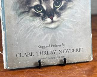 First edition of ‘Pandora, ‘ written and illustrated by Clare Turlay Newberry, published by Harper & Brothers. The book showcases charming illustrations and a story centered around a cat. It features a worn illustrated hardcover with signs of age-related wear, including scuffs and edge fraying. The interior remains intact with detailed illustrations and text reflective of Newberry’s style.