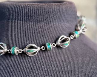 This lot features a beautiful necklace crafted from sterling silver and inlaid Malachite. Measures, 17” with a total approx. weight of 78.59 grams.