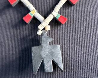 This lot features an antique Santo Domingo Pueblo (Kewa) Thunderbird necklace, an iconic style frequently made during the Depression era using repurposed materials like plastic from battery casings, phonograph records, and turquoise. This necklace has mosaic inlay typically utilizing turquoise, coral, and black jet (often repurposed plastic). These necklaces are highly collectible examples of Southwestern cultural heritage and resourcefulness. Handcrafted by artists from the Kewa (Santo Domingo) Pueblo, with many historic examples dating back to the 1920s–1940s. Measures, 22”.