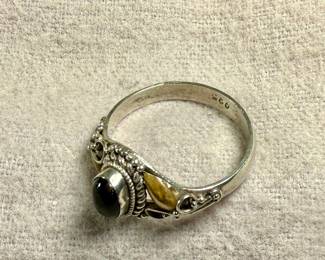 This lot features a vintage handcrafted ring made of sterling silver with an onyx center stone and gold accents. The purity of the gold is untested. This ring comes in a size 7 with a total approx. weight of 2.28 grams.