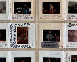 Vintage 35mm slides primarily organized in a transparent holder. Each slide features labels with the name “Richard Creamer” and addresses in Beverly Hills and Los Angeles, CA. Subjects documented include notable music acts such as The Police, David Bowie, ELO, and others. Handwritten annotations accompany several slides. Great condition for archival or display purposes.