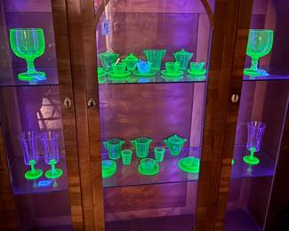 Akro agate child’s tea set and other uranium glass in an art deco backlight cabinet