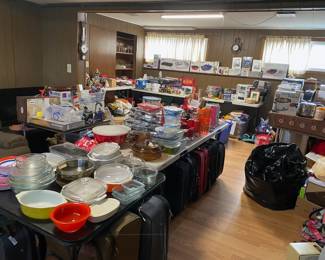 Lots of dishes, pans, some still in boxes, lots of luggage too