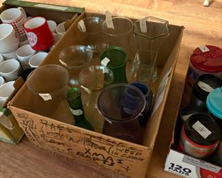 Various colors and sizes of bud vases and larger vases - under table in kitchen
