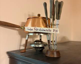 Copper fondue pot with utensils in kitchen