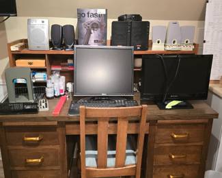 Small, wood desk. Monitors, keyboard, speakers and office supplies
