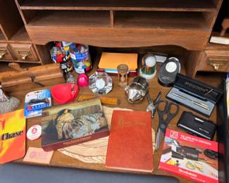 Desk drawer contents with pens books and collectibles