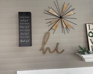 decorative wall sculpture featuring a starburst design with wooden elements and black metal spikes, paired with a cursive "hi" sign