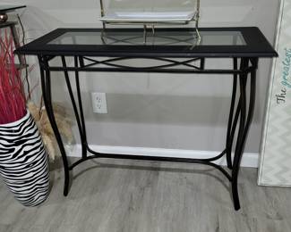 black metal and glass console table with a rectangular glass insert and curved legs.