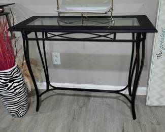 Console table with a black metal base and glass top