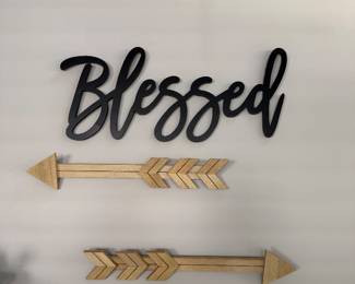  wall decor featuring a black scripted "Blessed" sign and two wooden arrow accents. 
